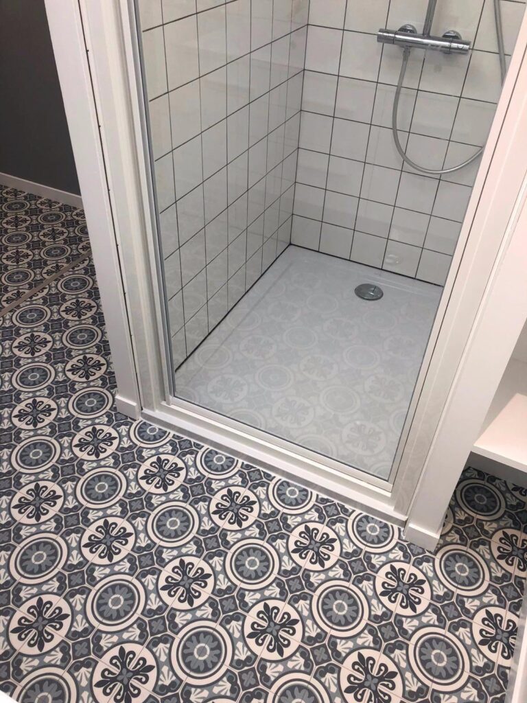 cabine de douche blanche et sol en carreaux de ciment