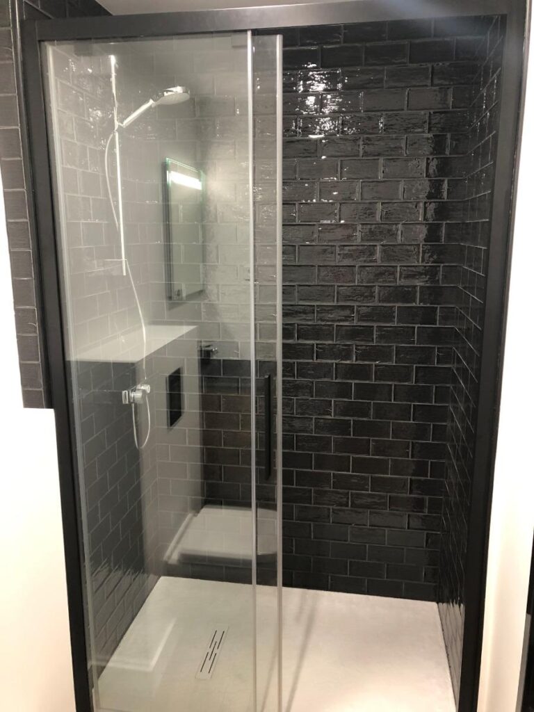 cabine de douche avec carreaux noirs et porte vitrée