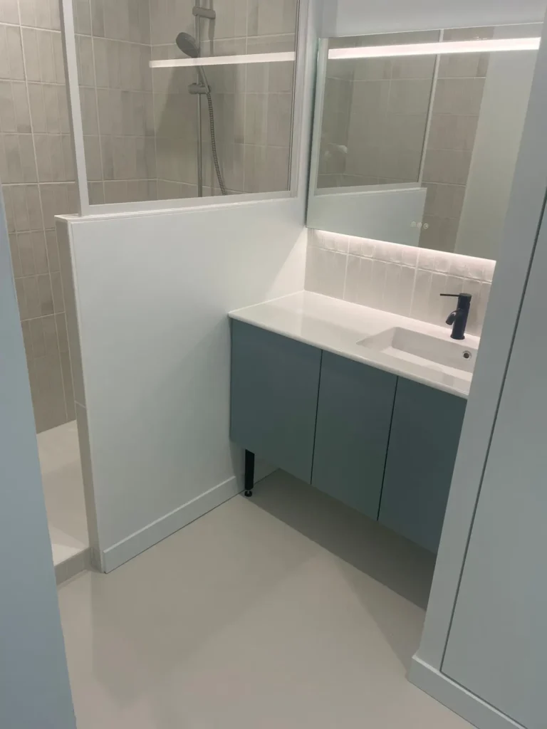 salle de bain rénovée dans les ton bleu clair et blanc avec cabine de douche et vasque moderne