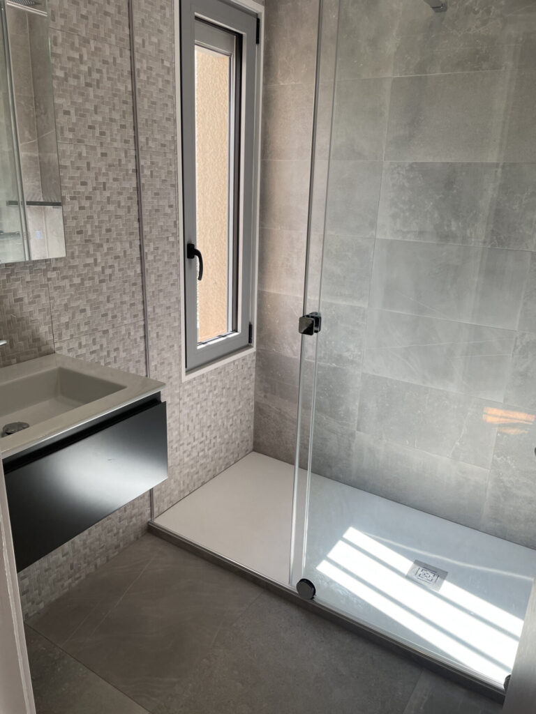 salle de bain avec mur en mosaïque et douche à l'italienne